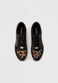Des baskets noires avec des détails en imprimé léopard, présentant un extérieur en cuir lisse, un design à laçage et des accents dorés sur le côté et la languette.