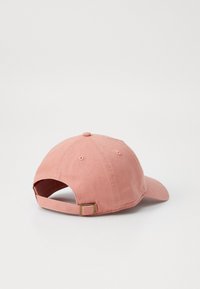 Állítható baseball sapka puha rózsaszín anyagból, ívelt napellenzővel, hat paneles kialakítással és fémcsattal a hátsó részen.