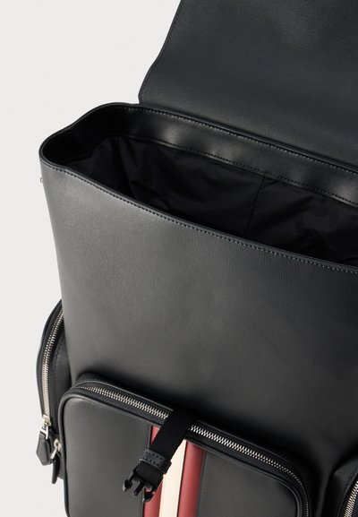 Black leather backpack with open top flap, a spacious main compartment, front zippered pocket, and red and white vertical stripes.