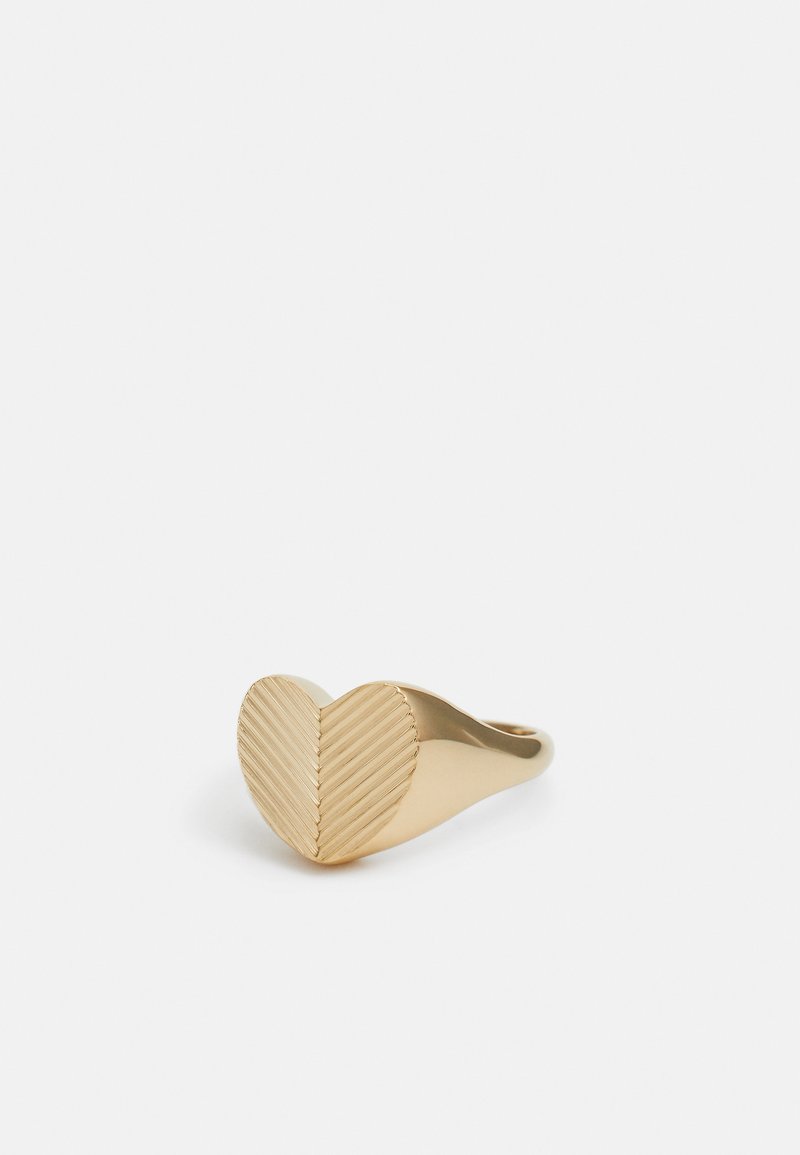 Goldfarbener Ring mit einem herzförmigen Design. Die Oberfläche weist diagonale Rillen auf, die ein strukturiertes Aussehen erzeugen.