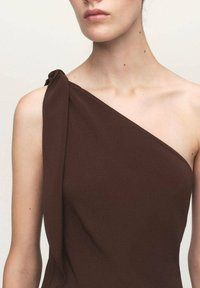 Asymmetrisches braunes Kleid aus einem weichen, strukturierten Stoff; verfügt über eine geraffte Schulter mit einem gebundenen Akzentdetail.