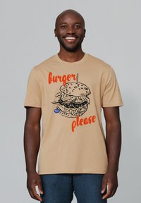 Beige t-shirt met een graphic van een gelaagde hamburger met de tekst "burger graag" in vet oranje erboven. Korte mouwen, ronde halslijn.