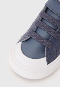 Modré kožené tenisky s bílou gumovou podrážkou, s tkanicemi z texturované látky a designem kulaté špičky. Prošité detaily podél horního okraje.