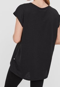 Schwarzes, kurzärmeliges, locker sitzendes T-Shirt mit Rundhalsausschnitt und längerem Rückensaum, aus weichem Baumwollstoff gefertigt.