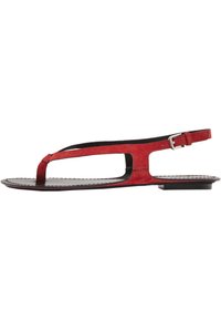 Rote Wildledersandale mit flacher Sohle, T-Strap-Design, verstellbarem Knöchelriemen und Ausschnitten an den Seiten.