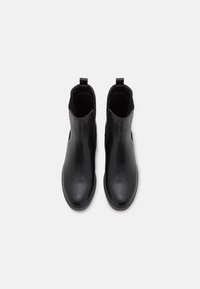 Botas tobilleras de cuero negro con textura suave, puntera redondeada, paneles laterales elásticos y tiradores para ponerlas con facilidad.