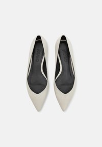 Ballerines à bout pointu en cuir lisse blanc cassé, présentant une ouverture sculptée et des semelles intérieures noires rembourrées avec un détail de logo.