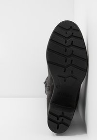 Semelle de botte noire avec des motifs de crampons profonds, taille 37, marquée "s.Oliver", présentée à la verticale sur fond blanc.