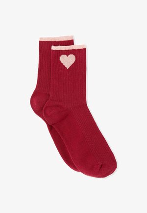Chaussettes rouges côtelées avec un bord rose et un motif de cœur sur le côté. Texture douce et design classique à la cheville.