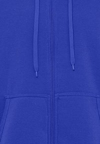 Blå zip-up hoodie med en glat tekstur, der har snore og frontlommer. Lynlåsen løber lodret ned gennem midten.