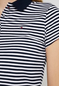 Pánská polo košile s námořnickými a bílými pruhy, vyrobená z texturované látky, s límečkem, krátkými rukávy a malým logem na hrudi.