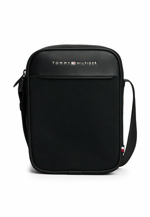 Czarna torba na ramię z teksturowanej tkaniny, z zamkiem błyskawicznym, przednią kieszenią i regulowanym paskiem. Posiada logo Tommy Hilfiger i kolorowe akcenty.