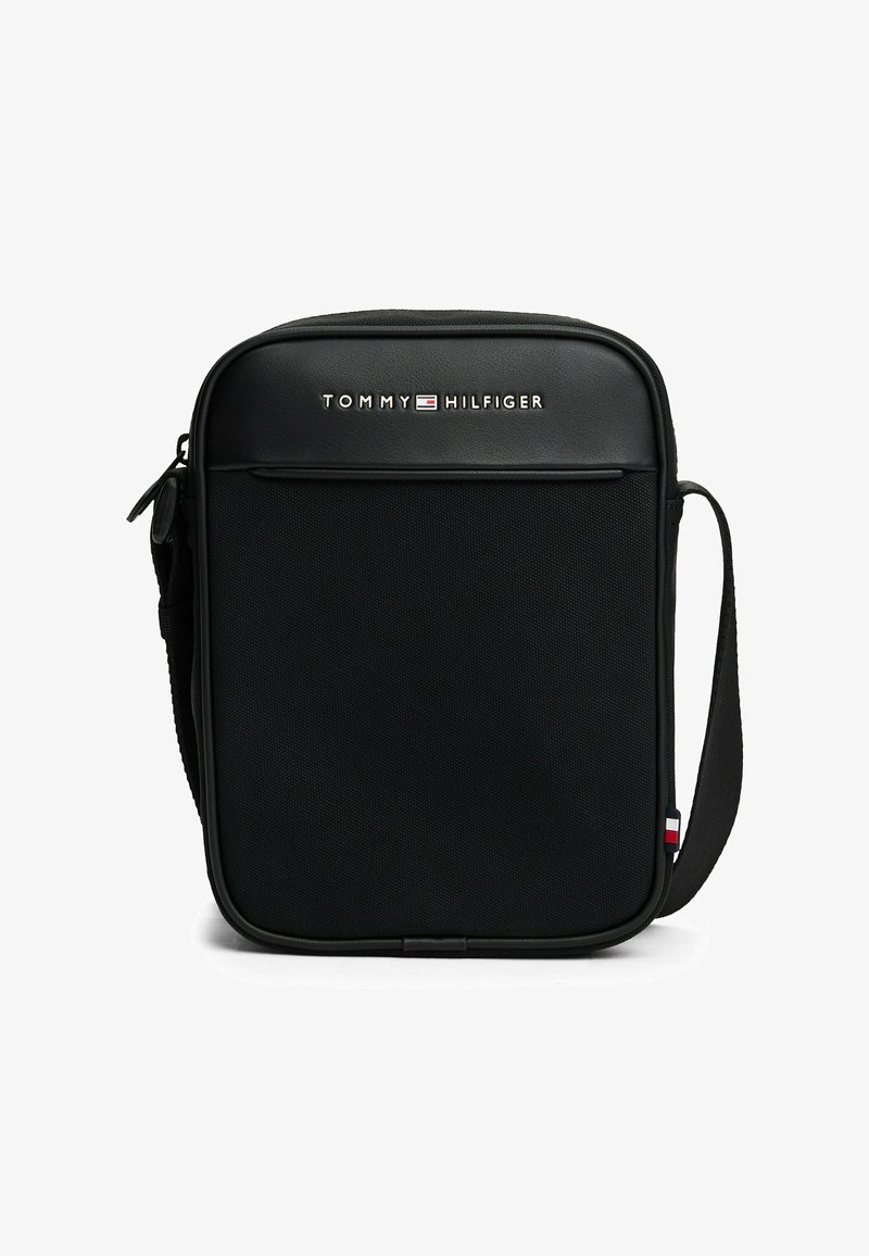 Schwarze Umhängetasche aus strukturiertem Stoff, mit Reißverschluss, Fronttasche und verstellbarem Riemen. Mit Tommy Hilfiger-Logo und farblichen Akzenten.