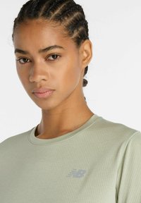 Light green moisture-wicking athletic shirt with a round neckline and subtle mesh texture. Features a small gray logo on the chest.