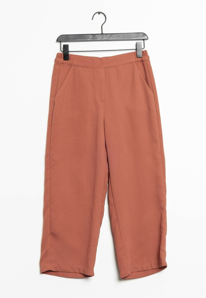 Pantalon court à larges jambes de couleur rouille accroché à un cintre noir à pinces sur fond blanc.