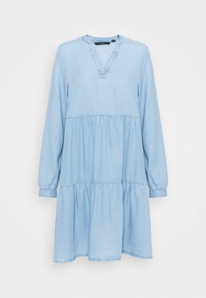 Robe décontractée bleu clair à manches longues avec jupe à volants et décolleté en V sur fond uni clair.