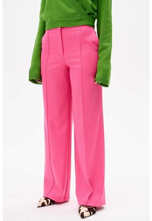 Roze wijde broek met een gladde textuur, voorzien van voorwaartse plooien en een hoge taille, gecombineerd met een groene trui en geruite hakken.