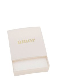 Rechteckige, crèmefarbene Box mit einem leicht gewölbten Deckel; "amor" in goldener Schrift auf der Vorderseite. Glatte Oberfläche, offenes Innere zur Aufbewahrung.