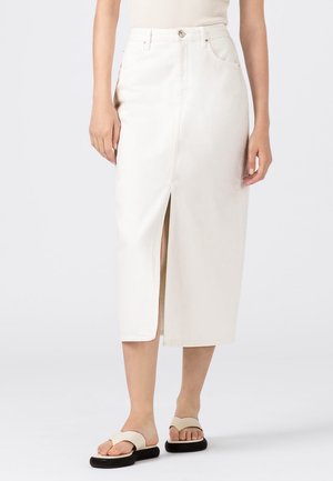 Witte denim midi-rok met een voorkant split, klassiek vijf-pocket ontwerp en subtiele stiksels. Gecombineerd met platte beige sandalen.