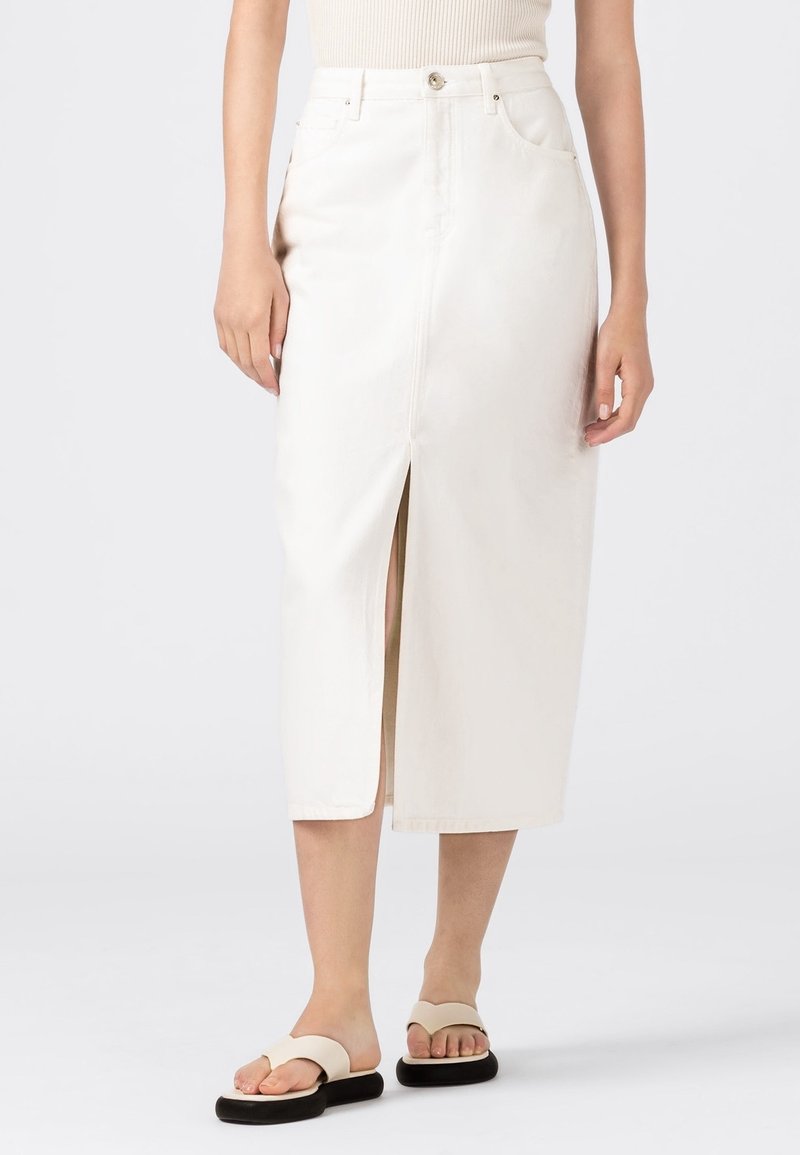 Bílé džínové midi sukni s předním rozparkem, klasickým pětipocket designem a jemným prošitím. V kombinaci s plochými béžovými sandály.