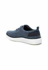 Zapato azul marino con una parte superior de tela texturizada, suela blanca ligera, forma redondeada y cordones, diseñado para uso casual.