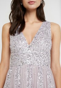 Lavendelfarbenes Kleid mit V-Ausschnitt, verziert mit Pailletten am Oberteil und weichem, plissiertem Stoff für den Rock.