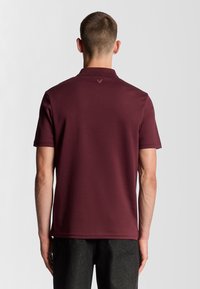 Kortærmet burgunder polo t-shirt lavet af bomuldsblanding, med et diskret logo på den øverste ryg og lige kant.