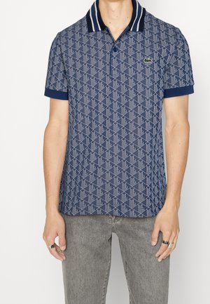 Marineblaues Polohemd mit geometrischem Muster, zweiknöpfiger Leiste, kontrastierendem gestreiftem Kragen und einfarbigen marineblauen Ärmeln. Hergestellt aus atmungsaktivem Stoff.