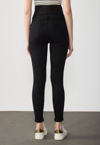 Svarta tajta jeans i denim med en slät yta, hög midja och femficksdesign. Bärs med vita plattformssneakers.
