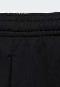 Pantalones deportivos negros con una banda elástica texturizada en la cintura y detalles de costura. El material es suave y tiene un acabado mate.