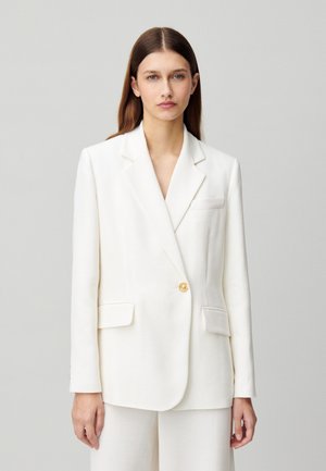 Blazer bianco con revers, bottone singolo dorato e due tasche frontali. Tessuto liscio con una vestibilità leggermente strutturata.