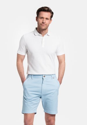 Chemise polo blanche à manches courtes et deux boutons, associée à un short bleu clair avec une fermeture à bouton et des poches latérales.
