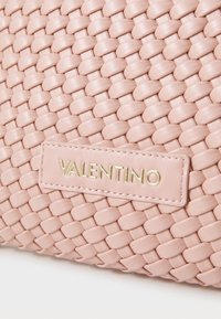 Spleciona różowa skórzana torebka wyróżniająca się gładką teksturą i złotą plakietką z logo. Solidna konstrukcja z misternym wzorem splatania.