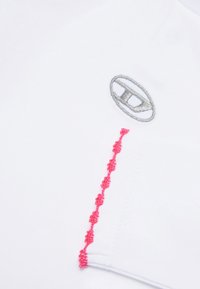 Tessuto bianco con logo argento in alto a sinistra e una cucitura decorativa rosa lungo il lato destro. Texture liscia.