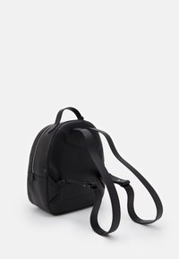 Black leather backpack with a rounded shape, featuring adjustable straps, a top handle, and a zipper closure on one side.