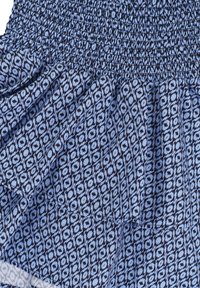 Blauwe en marineblauwe gestikte stof met een gesmokete textuur; heeft een geometrisch ontwerp van diamanten en cirkels. Zacht, lichtgewicht materiaal.