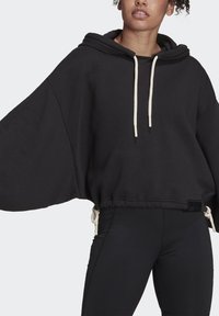 Hoodie nero oversize con maniche larghe, cordini regolabili e tasca a marsupio, realizzato in morbido tessuto per garantire comfort.
