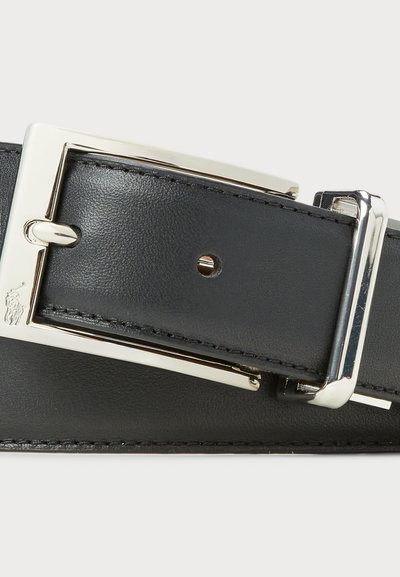 Ceinture en cuir noir avec une boucle rectangulaire en métal argenté poli. Présente des coutures visibles et un emblème décoratif embossé sur la ceinture.
