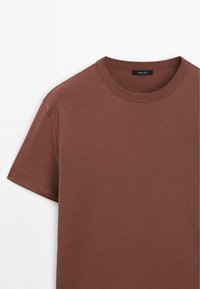 Bruin T-shirt met korte mouwen gemaakt van zacht katoen, voorzien van een ronde hals en nette stiksels langs de mouwen en zoom.