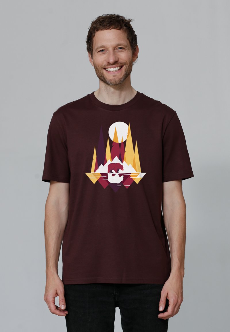 Bordeaux katoenen T-shirt met een geometrisch grafisch ontwerp in oranje, geel en wit, dat bergen en een zon afbeeldt. Korte mouwen.