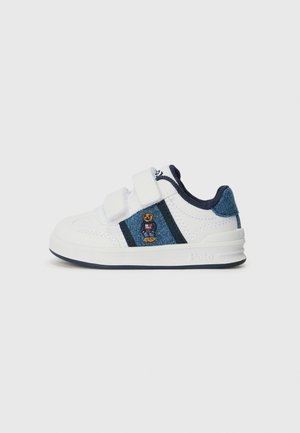 Zapatilla blanca con acentos de mezclilla, con correas de velcro, logo de oso bordado y una suela de goma texturizada.