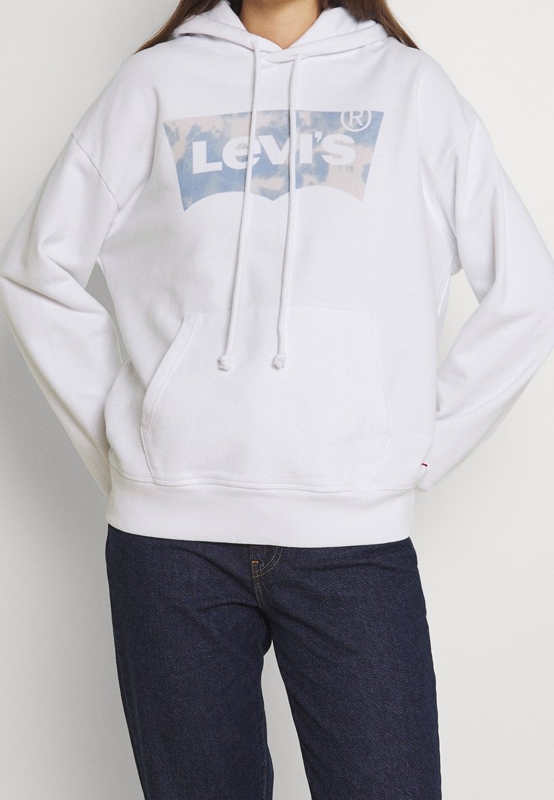 Bílá mikina s kapucí a předními klokankovými kapsami, se grafickým logem Levi's v modro-bílé barvě. Materiál z bavlny, uvolněný střih.