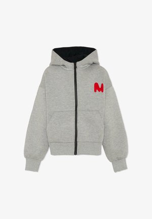 Haut à capuche zippé gris avec une capuche doublée en noir, des poches avant et un logo "M" rouge sur la poitrine gauche. Fabriqué en tissu doux et texturé.