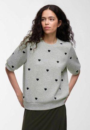 Grijze hoodie met korte mouwen, voorzien van zwart hartpatroon dat gelijkmatig verspreid is, geribbelde ronde hals en een relaxed fit bij de taille.