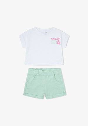 Camiseta blanca de manga corta y corte corto con "VACAY MODE ON" y hibisco rosa, combinada con pantalones cortos de dobladillo enrollado en verde menta con cintura elástica y bolsillos.