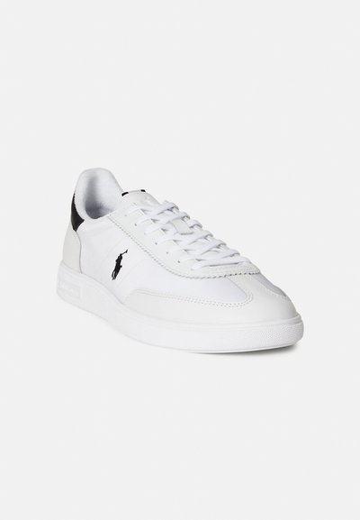 White sneaker made of leather and synthetic materials, featuring a textured rubber sole, lace-up design, and a black accent at the heel.