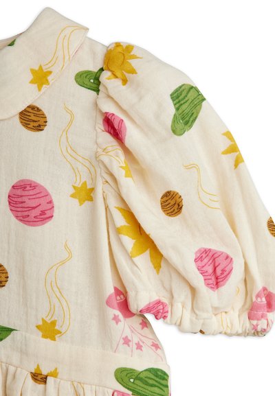 Ύφασμα εκρού με φουσκωτό μανίκι που φέρει πολύχρωμα σχέδια με θέμα το διάστημα, συμπεριλαμβανομένων πλανητών, αστέρων, κομητών και πράσινων πυραύλων.