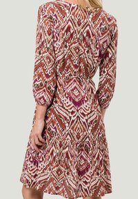 Robe à motifs multicolores avec un design floral dans des tons de rouille, rose et crème, dotée de manches bouffantes et d'une jupe à volants.