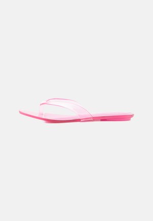 Sandalia plana rosa transparente con una sola correa ancha que cruza la parte superior, mostrada de lado sobre un fondo blanco.