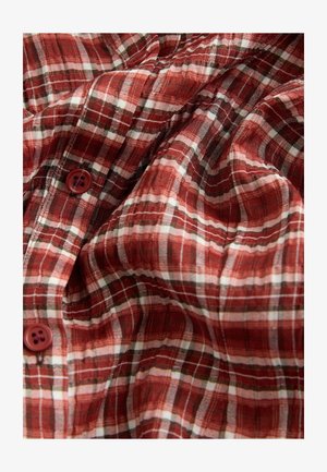 Czerwona i biała tkanina w kratę o lekkiej strukturze, z czterema guzikami. Wzór zawiera cienkie czarne linie dla detalu.